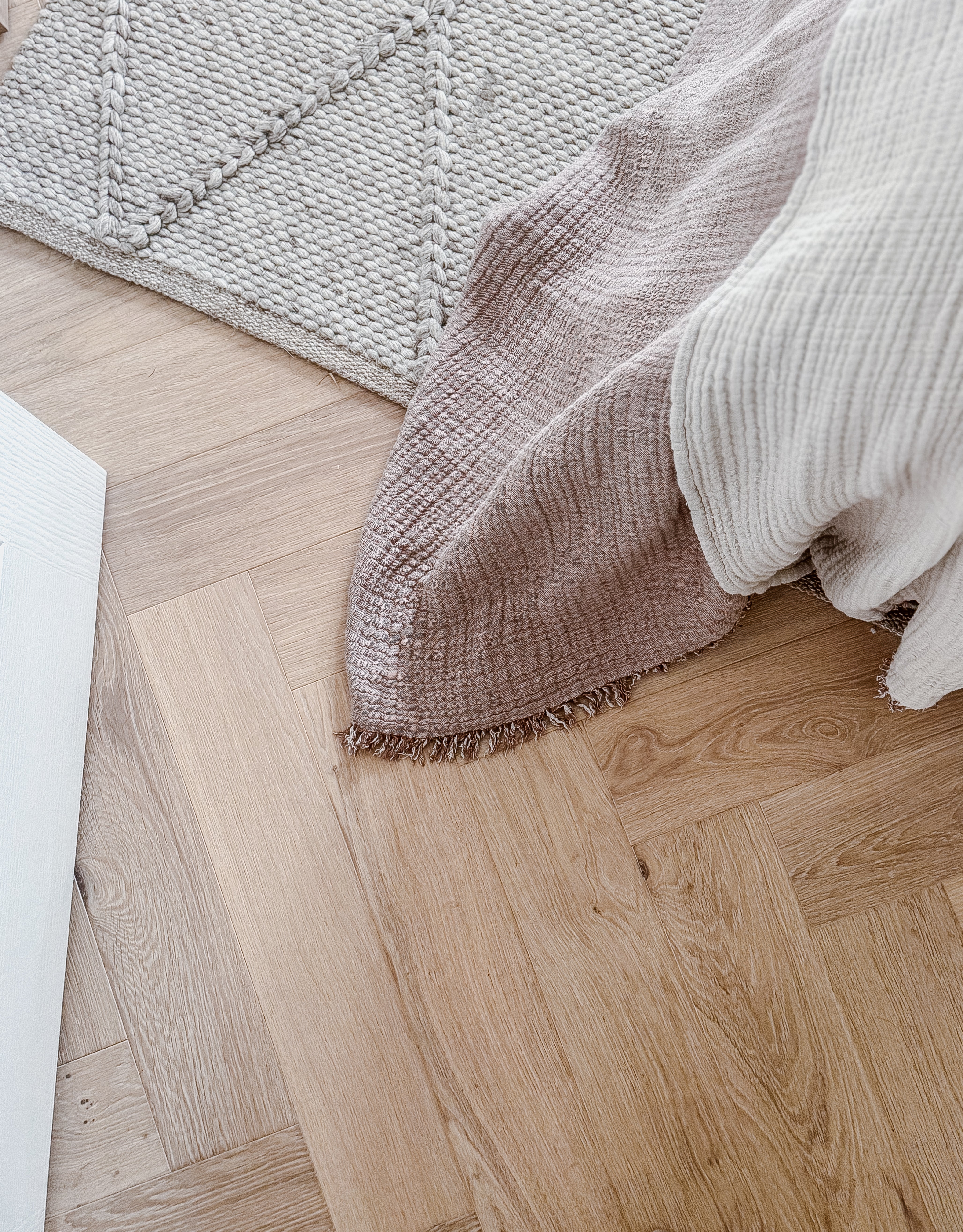 Blonde oak timber flooring in a herringbone pattern with a warm matte finish for a modern, minimalist interior.